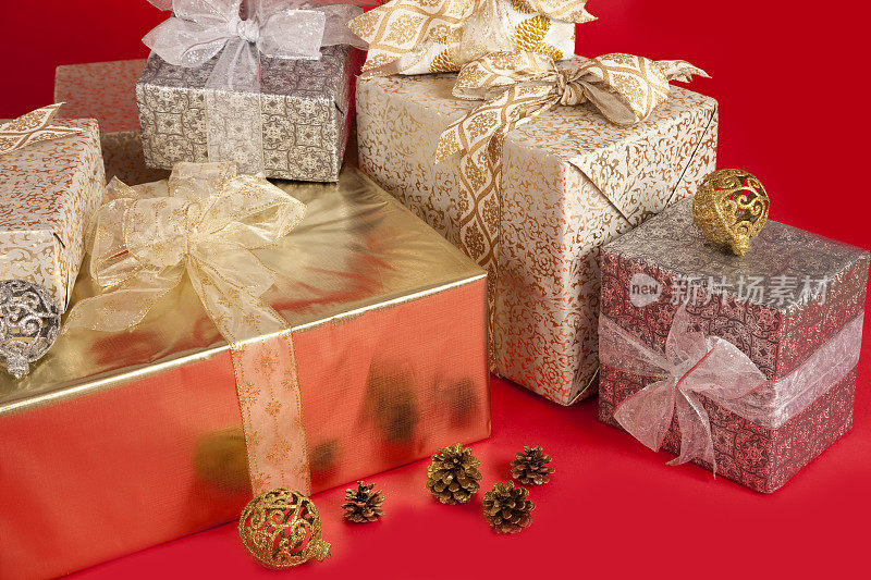 带蝴蝶结的圣诞礼物，松果和圣诞球。包裹在红色背景上