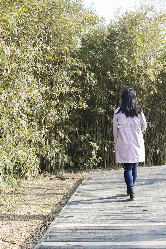 年轻女性拿着一次性杯子走在公园小径上