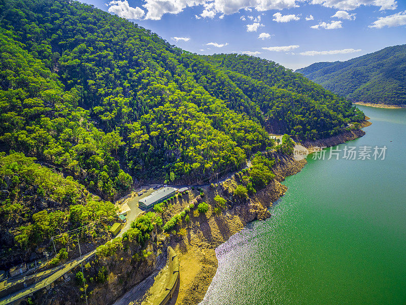 在晴朗的夏日里，湖面和森林覆盖的山丘上白云飘飘