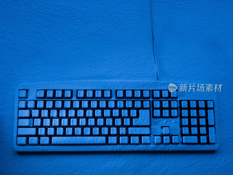 电脑键盘站在覆盖着雪的表面上，用蓝色的霓虹灯照亮了copyspace
