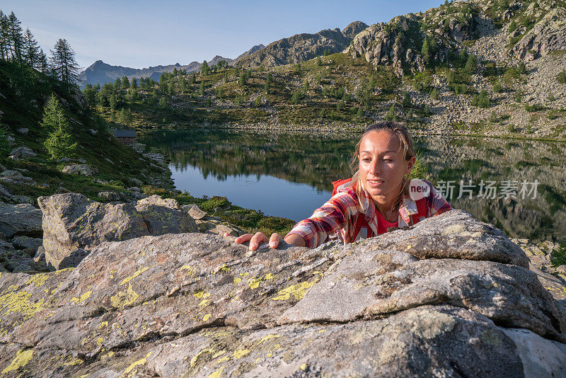 女攀登者攀登山顶;湖景