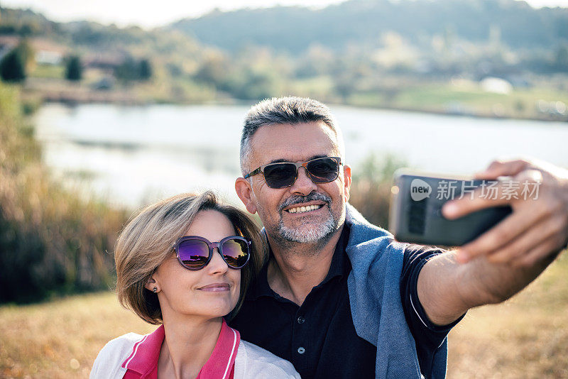 一对老年夫妇在大自然中用智能手机拍照