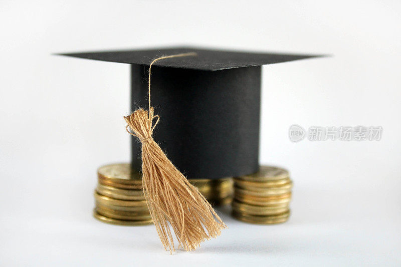 为概念金融和教育奖学金储蓄硬币的毕业上限。毕业文凭和金币上白色背景，概念投资教育，近距离，选择性聚焦，警察