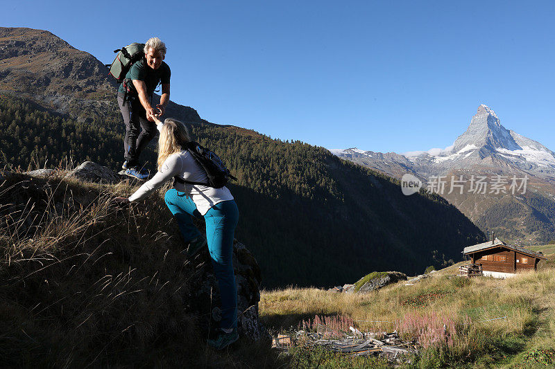 男性登山者帮助女性登山者爬上岩石