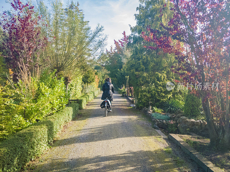 女孩，骑着自行车离开，在花园的自行车道