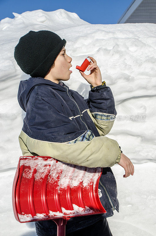 小男孩在铲雪后使用哮喘泵