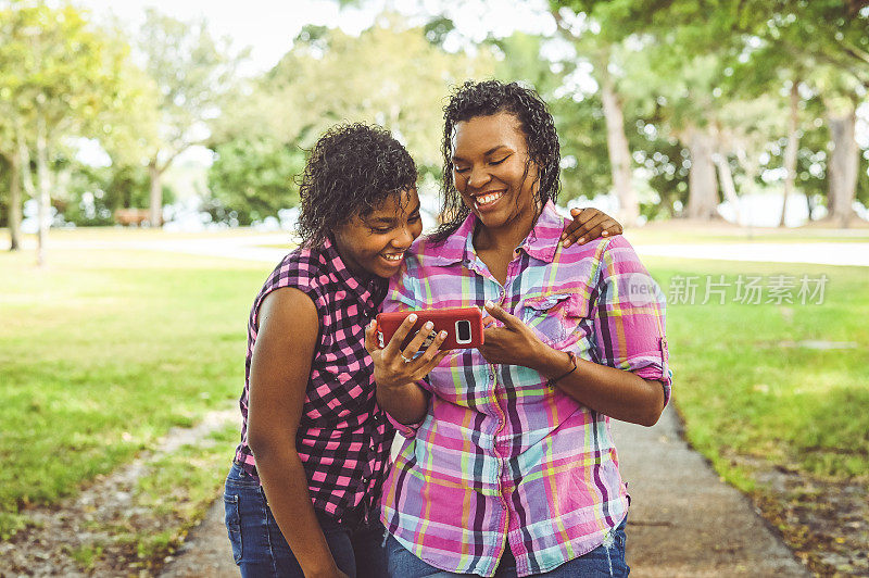 妈妈和十几岁的女儿一起对着电话笑，团结和科技