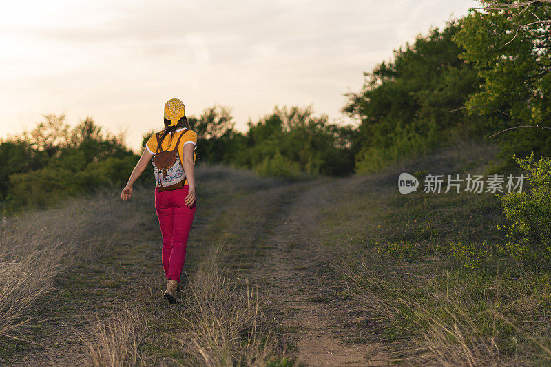 在春天搭便车。在大自然中享受阳光的女孩。