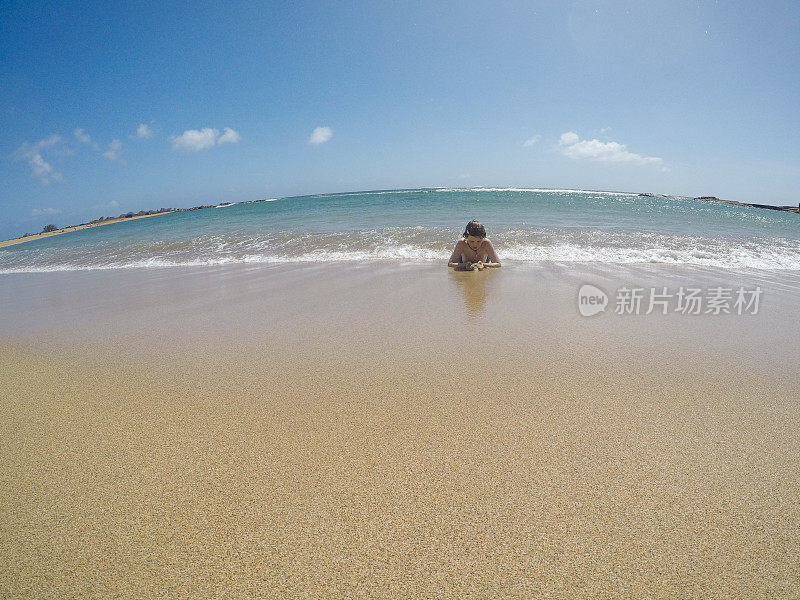 在天堂里游泳，孩子们在考艾岛的海洋里游泳，在荒芜的海滩上玩耍