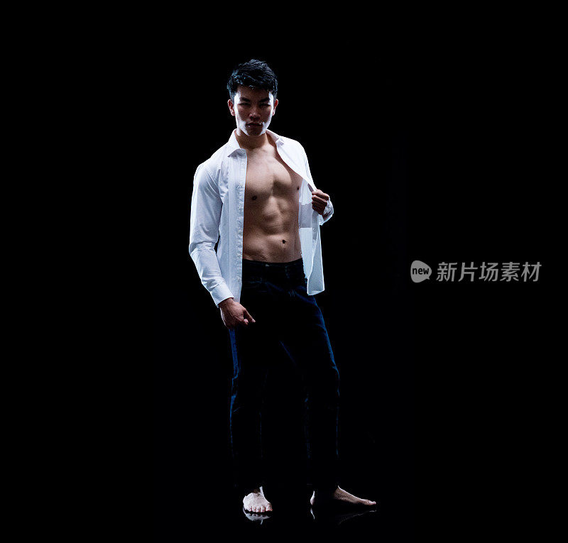 东亚人种男性穿着衬衫站在黑色背景前穿衣服