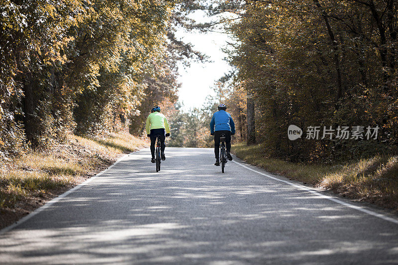 两个成年人在秋天的乡村公路上骑车