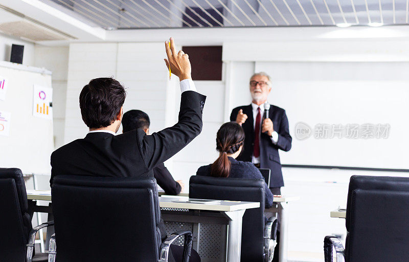 在研讨会会议室，商人举手向演讲者提问