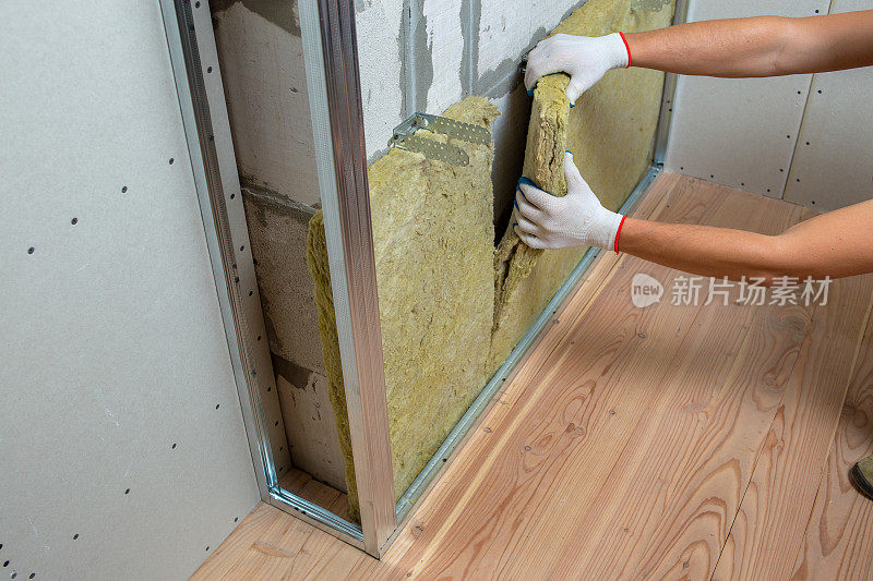 工人用矿物岩棉隔热隔离房间墙壁。