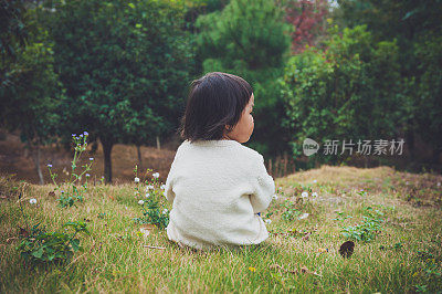 一个中国女孩坐在花园里的草地上