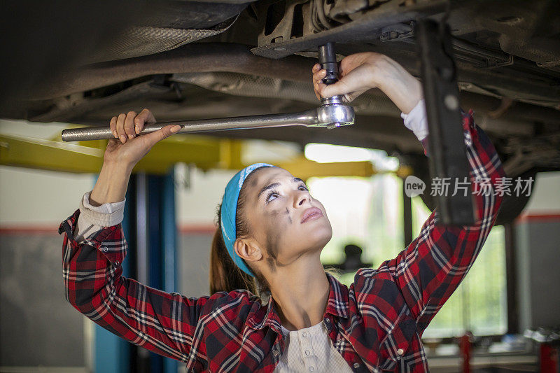 美丽的女机修工在修车厂修车。