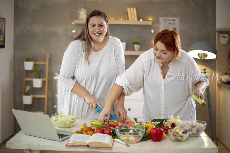 年轻微笑的胖女人用笔记本电脑准备早餐。