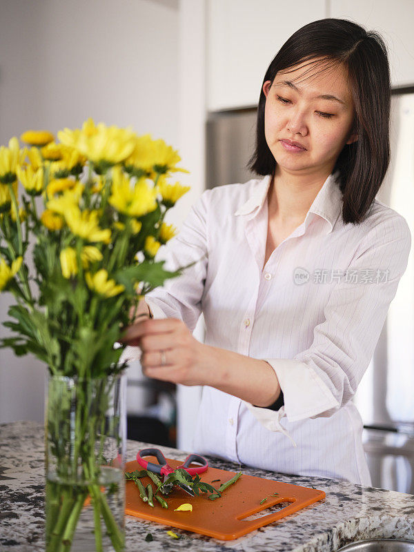 亚洲妇女在她的家里插花