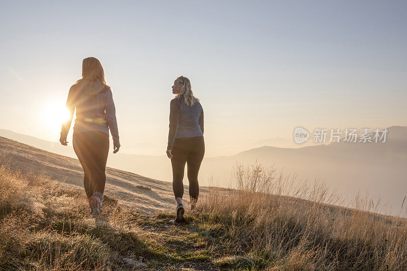 日出时，女徒步旅行者沿着草地行走