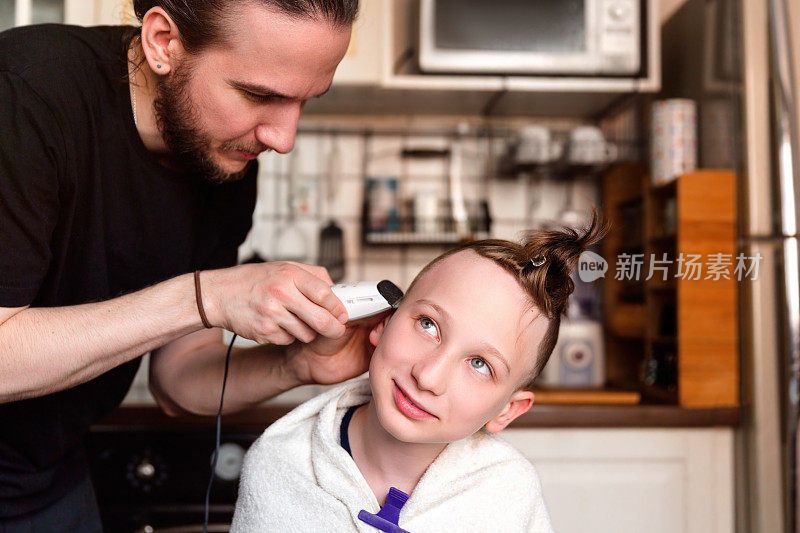 冠状病毒隔离期间，父亲在家用电动剃须刀剃儿子的头发