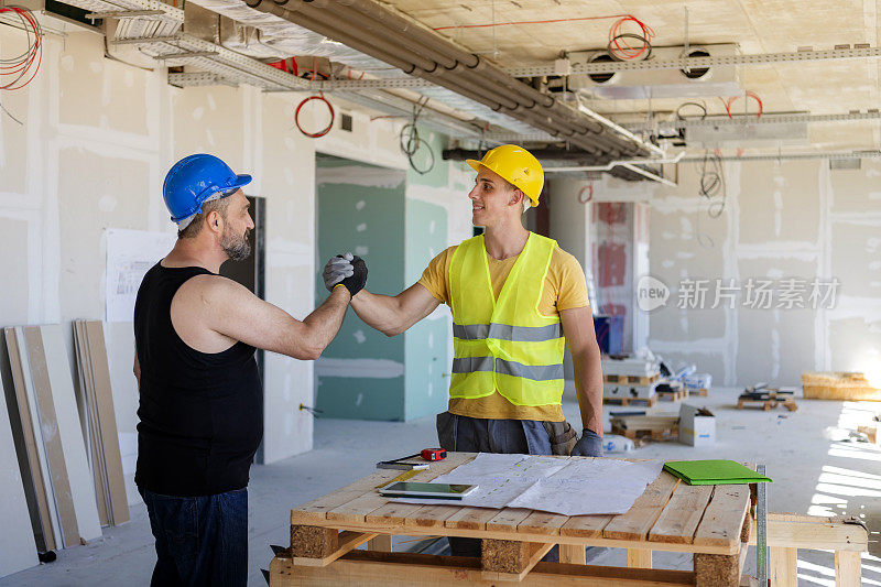 工人和建筑师在建筑工地握手。