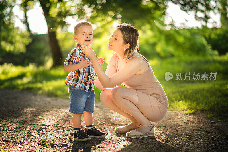 在森林里的户外散步中，母亲在安抚哭闹的孩子和蹒跚学步的小男孩