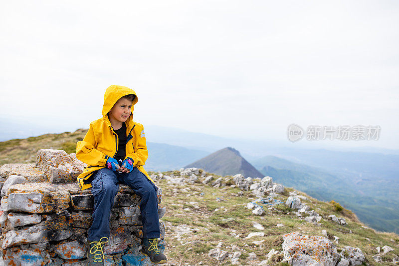 一个可爱的男孩坐在山顶上吃零食