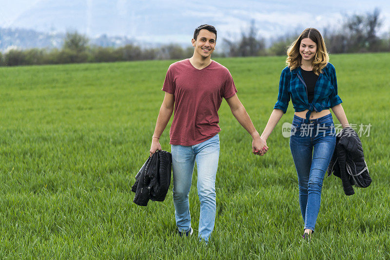 一对情侣在田野里散步，玩得开心。