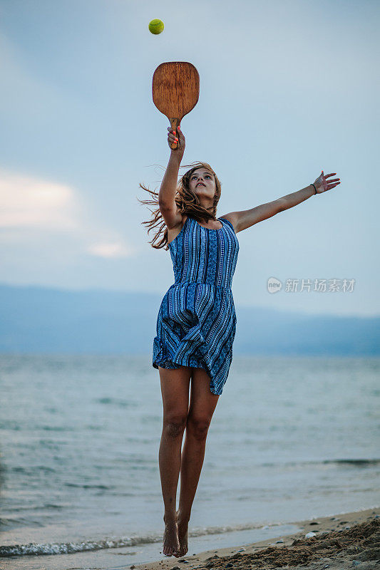 一个年轻女子在海滩上玩划桨球