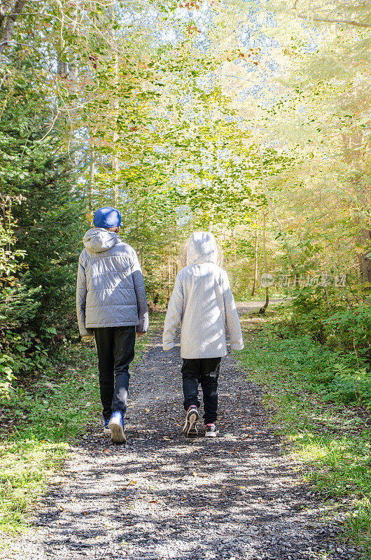 秋天的一天，两个孩子在森林小路上散步