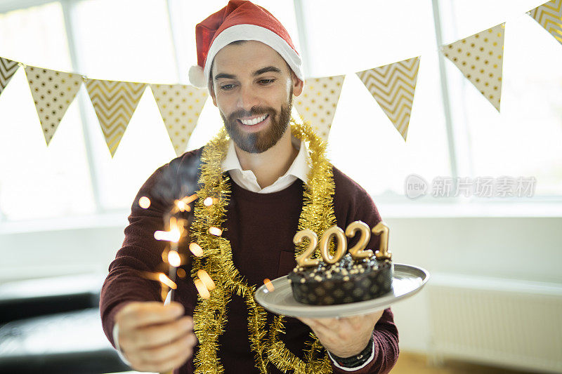 一个年轻人在家里用烟花和巧克力蛋糕庆祝新年