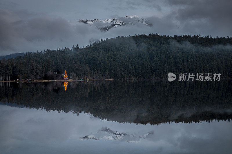 圣诞树灯倒映在湖与山景。