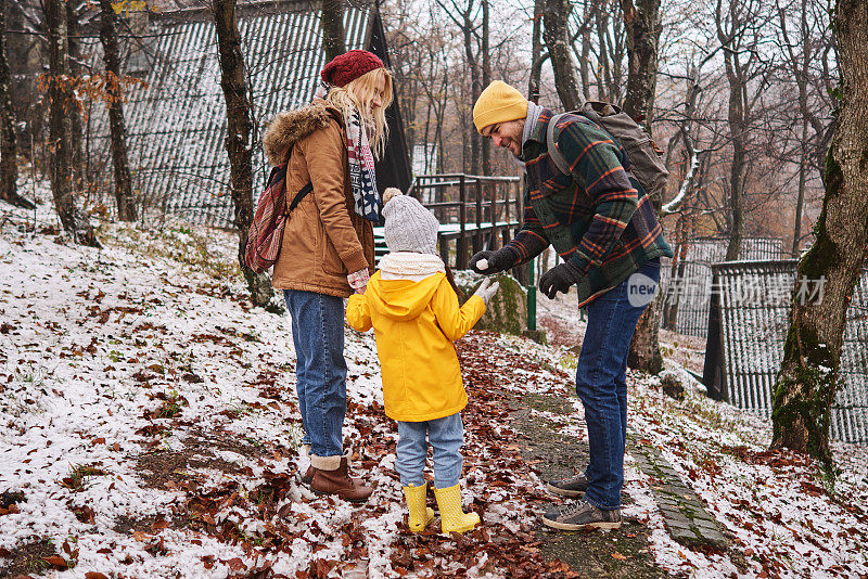 在他们散步的时候，慈爱的父亲做了一个小雪球，这样他可爱的女儿就可以在冬季家庭度假时玩得开心了