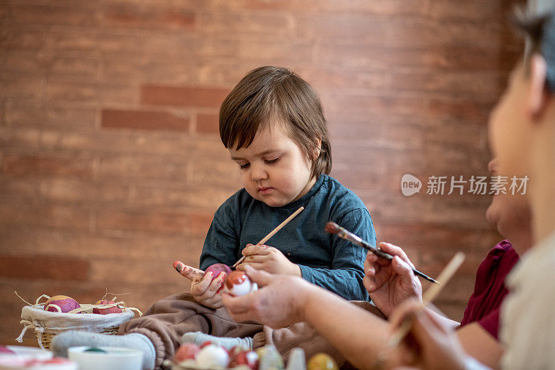 奶奶正在帮她的孙子为复活节涂彩蛋。