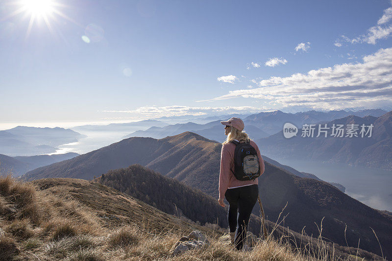 女性徒步旅行者沿着阳光明媚的山脊行走