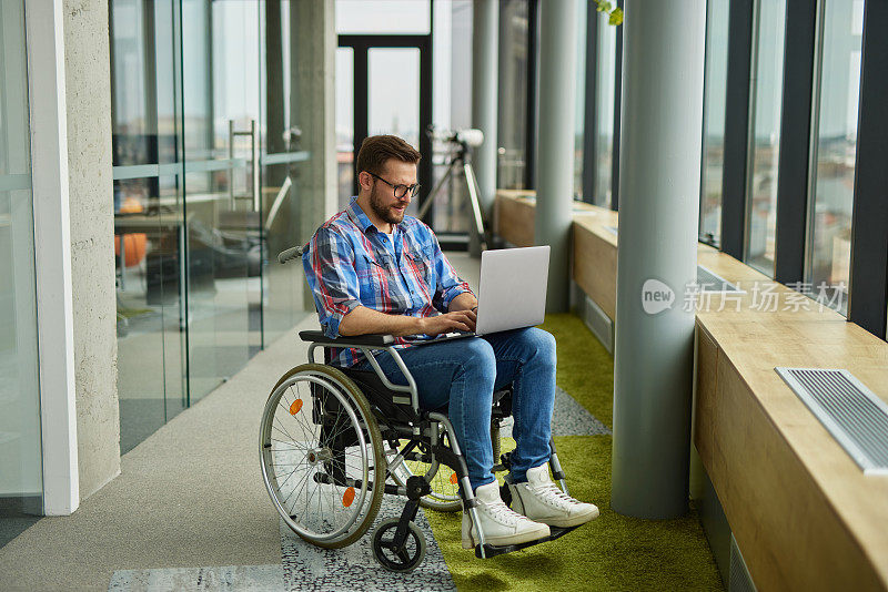 残疾人男性IT工作者在轮椅上使用笔记本电脑工作