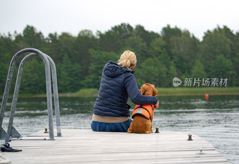 挪威维斯特福德，一个女人和她的小狗在码头上