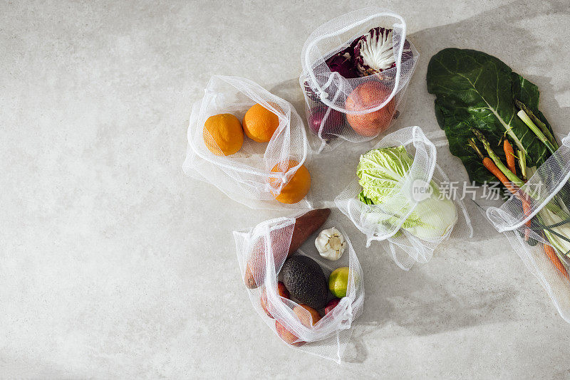 五彩缤纷的蔬菜和水果在厨房桌上的网袋