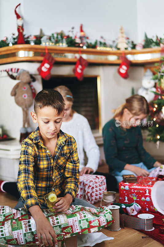 小孩子在圣诞树前包装和装饰圣诞礼物