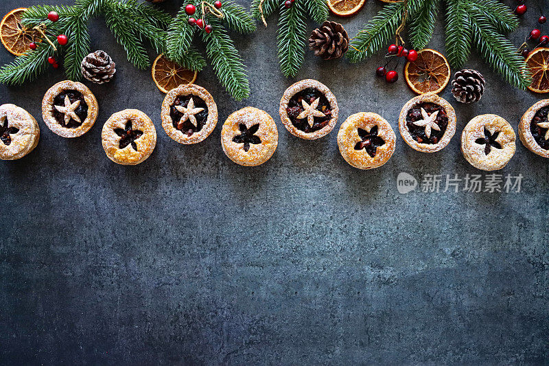 形象节日圣诞设计海报边界云杉针，红色浆果，松果，干橙柑橘水果片，糕点星星详细的盖子，节日圣诞甜点脆皮糕点与甜肉馅，灰色背景，复制空间