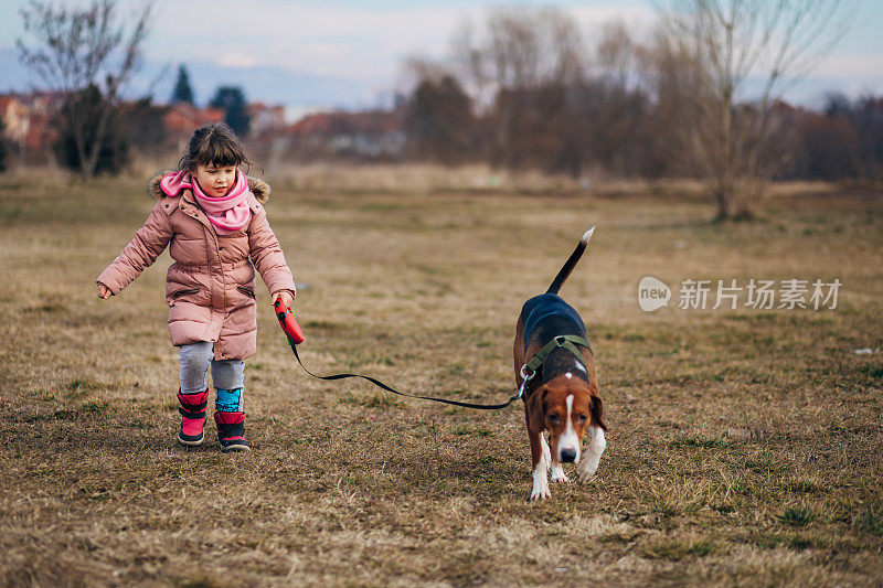 在一个寒冷的秋日早晨，一个漂亮的小女孩带着她的狗散步。