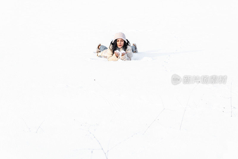 年轻女子在冬天的雪地里玩得很开心