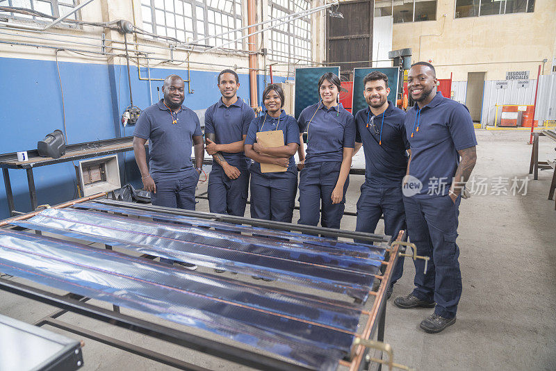 快乐的多种族工人在太阳能电池板工厂的肖像