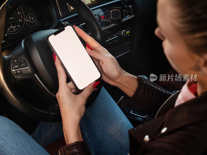 一个女人在车上用黑屏智能手机