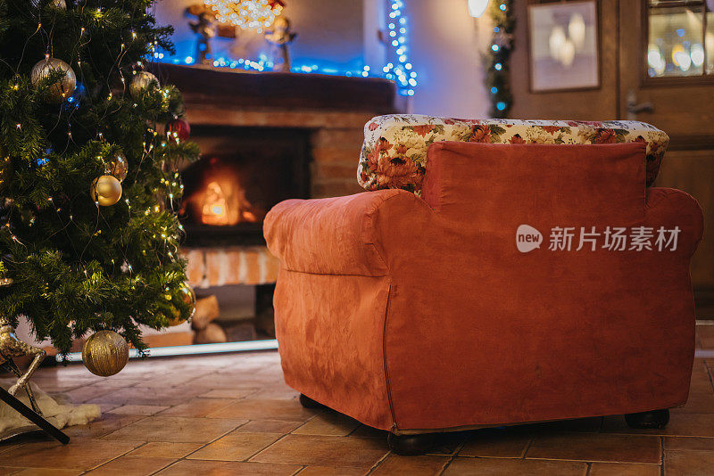 在装饰明亮的家里，圣诞树旁的舒适扶手椅空着