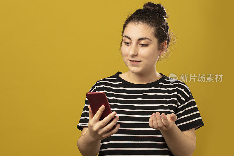 一个年轻漂亮的女孩使用智能手机的特写肖像