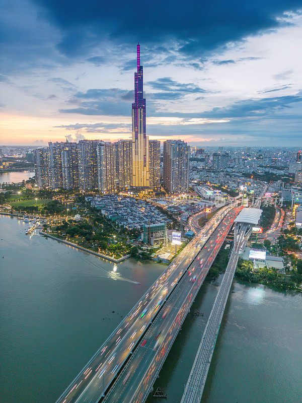 从空中俯瞰81号地标的日落景观——一幢超高的摩天大楼和西贡大桥，西贡河沿岸的发展在光线下十分流畅