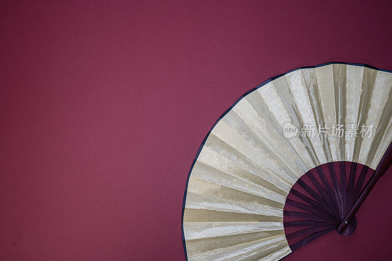 亚洲风格手持式米色扇子红色背景，中国新年主题，复制空间，文字的地方