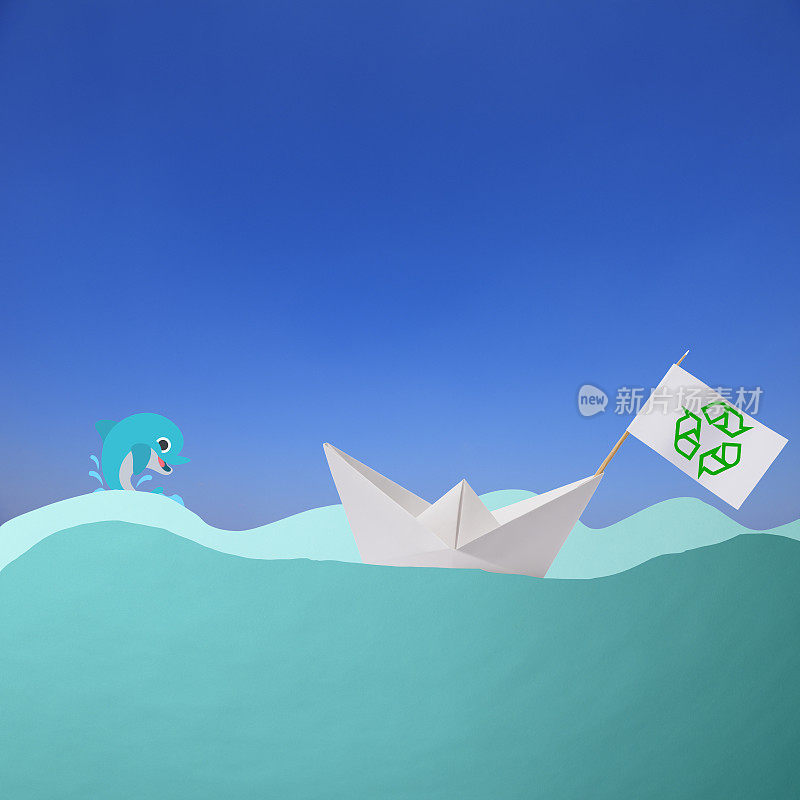印有绿色回收标志的纸船，以及跳跃的海豚