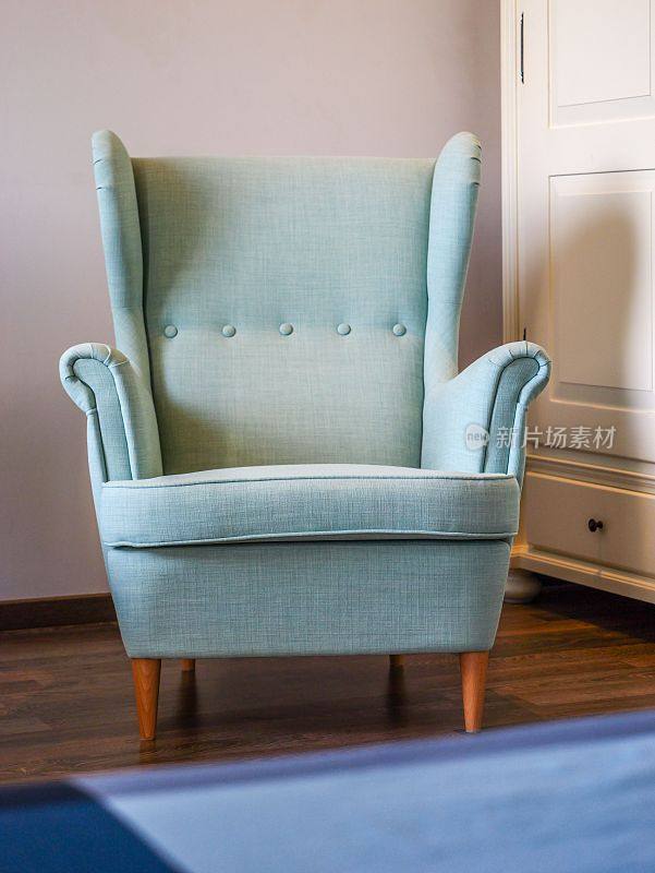 卧室里一张淡绿色的古董扶手椅，旁边是一张蓝色的地毯