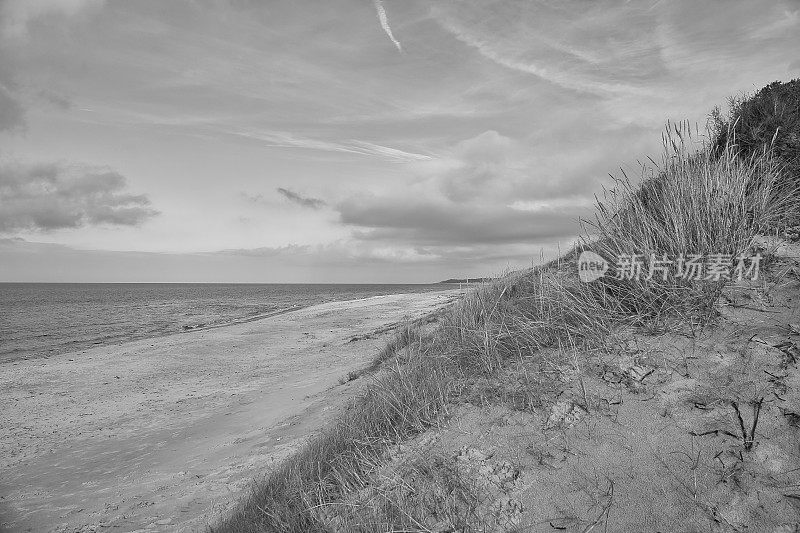 穿越丹麦海滩的黑白照片。沙丘，沙水